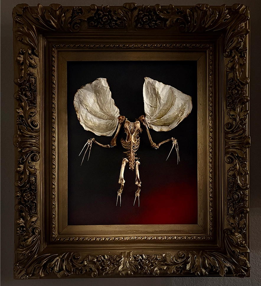 A striking full-body shot of the Dúlachán bone sculpture, featuring a headless skeletal demon holding its own skull, mounted within a custom black wooden frame.