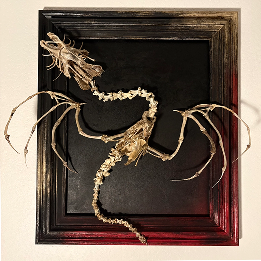 A full view of The Beithir bone sculpture, featuring a serpentine skeletal dragon body with large articulated wings, mounted on a dark atmospheric background.